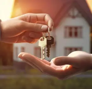 Remise de clés entre deux personnes devant une maison, symbolisant la concrétisation d’un projet d’achat immobilier.