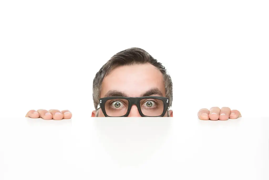 Homme surpris qui regarde au-dessus d’un panneau blanc