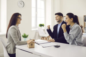 Une courtière immobilière échange avec des clients assis autour d’une table, illustrant un accompagnement personnalisé et une approche centrée sur les acheteurs.