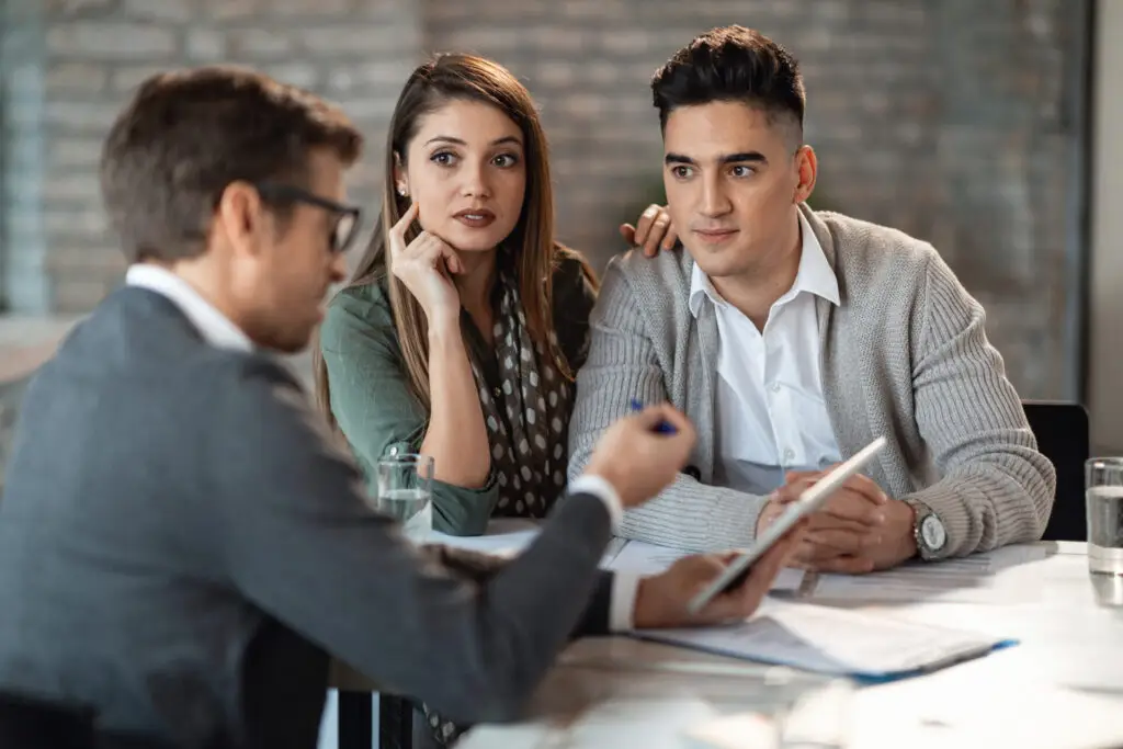 Couple en discussion avec un courtier immobilier pour préparer un achat résidentiel.