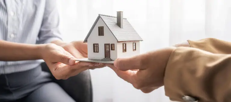 Remise symbolique d’une maison entre deux personnes, représentant une transaction immobilière confidentielle.
