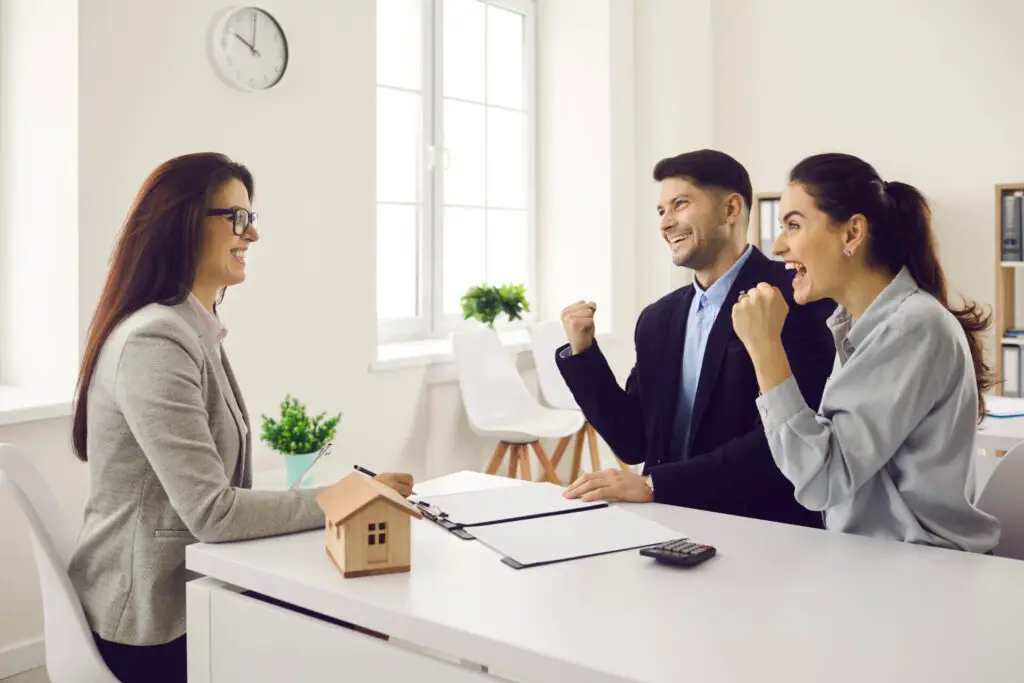 Professionnelle en immobilier expliquant un contrat à un couple dans un bureau lumineux