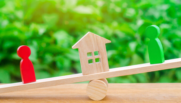 Balance en bois déséquilibrée entre deux figurines et une maison, symbolisant le déséquilibre dans une transaction immobilière.