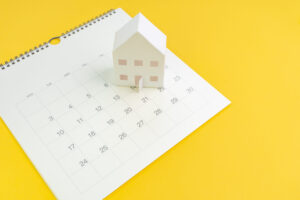 Calendrier avec une maison miniature illustrant la planification d’un achat immobilier