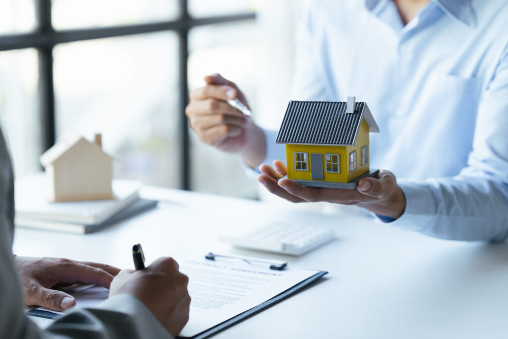 Acheteur(euse) analysant un projet d’achat immobilier avec maquette de maison et documents financiers