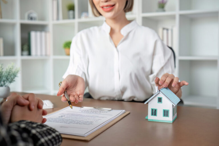 Courtière immobilière souriante tenant la clé d'une nouvelle maison dans sa main pour la remettre à l'acheteur.