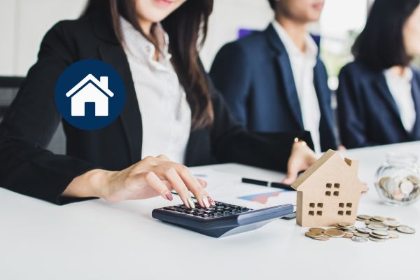 Rencontre professionnelle autour d’un financement hypothécaire résidentiel, avec calculatrice et maison miniature.